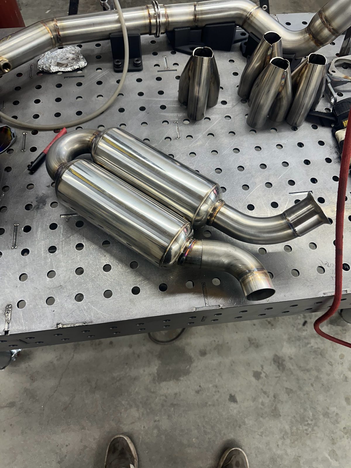 Stainless muffler assembly on a weld table at Tomlin Performance