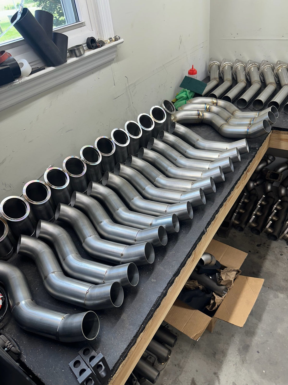 Row of bent metal tubes lined up on a shop bench