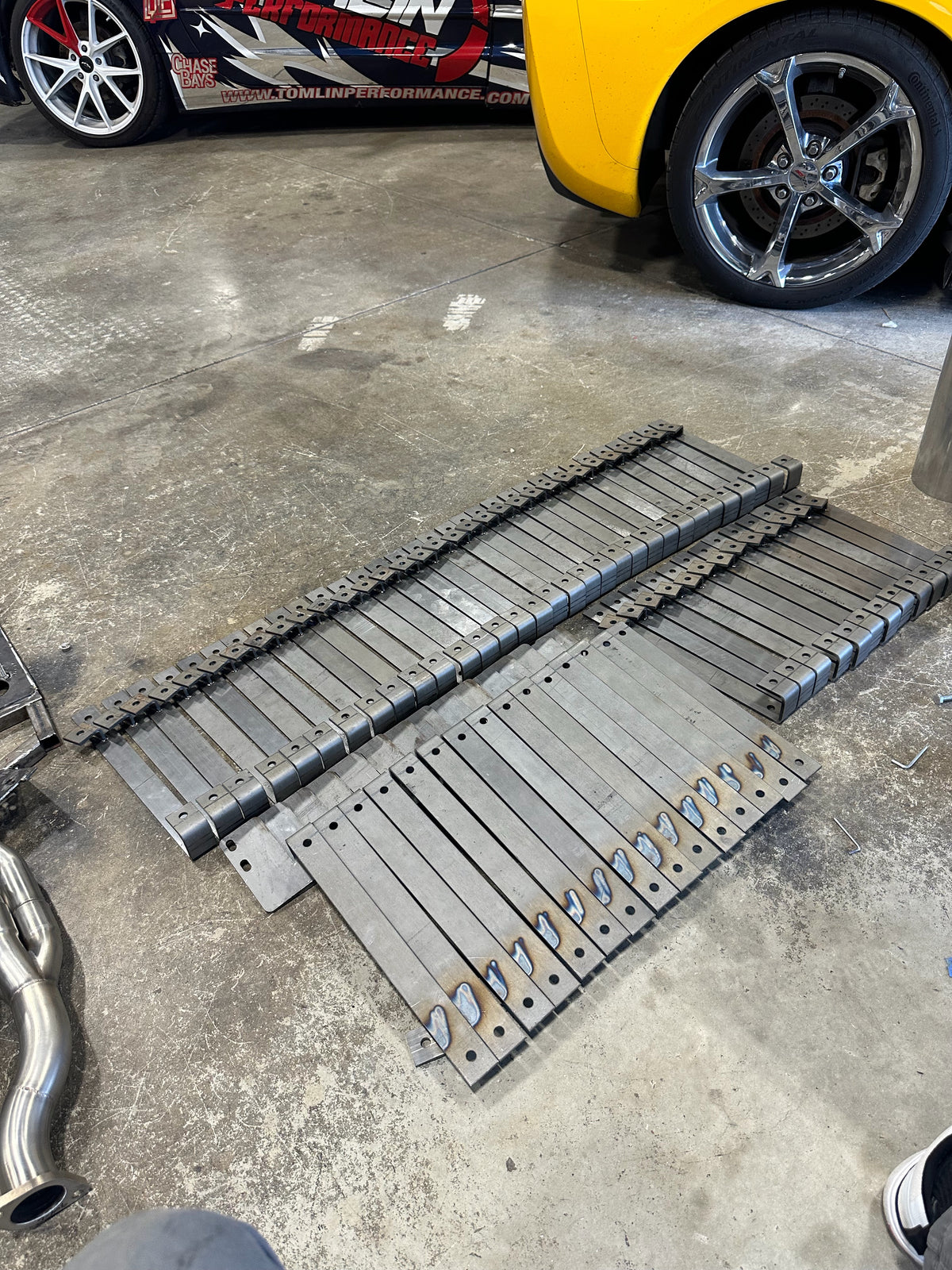 Batch of laser-cut steel brackets on the Tomlin Performance shop floor