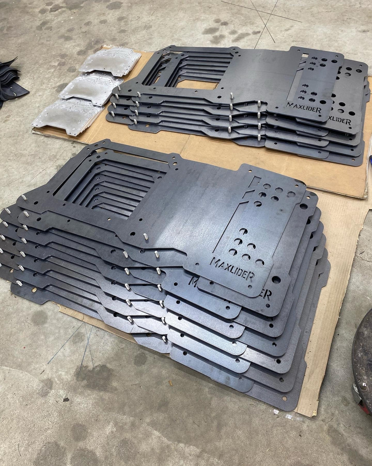 Stacks of CNC-cut plates with the MAXLIDER logo
